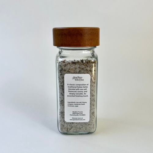 A clear glass bottle of seasoning salt with a light brown wooden lid, set against a plain white background.