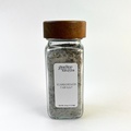 A clear glass spice jar filled with seasoning salt, featuring a medium brown wooden lid and a white label that reads 'Giardino Foresta Scarborough Fair Salt'. The jar is centered against a clean white background.